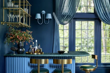 Bold blue bar room with deep navy walls, fluted blue cabinetry, brass detailing, and green leather stools, designed by Andrew Suvalsky Designs in Great Falls, Virginia