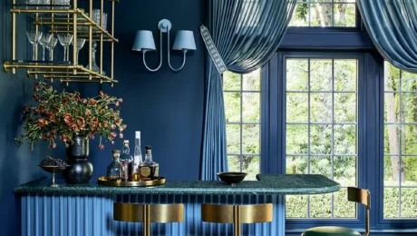 Bold blue bar room with deep navy walls, fluted blue cabinetry, brass detailing, and green leather stools, designed by Andrew Suvalsky Designs in Great Falls, Virginia
